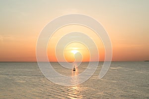 Sailboat on the water of the sea at sunset in scarlet color.