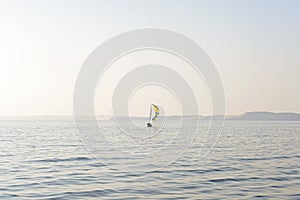 Sailboat with yellow blue striped sail in the sea.