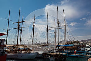 Sailboats with lowered sails are moored on the pier.