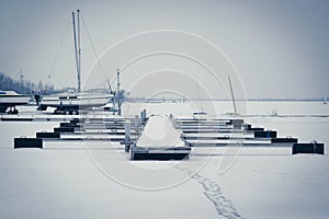 Sailboats moored in foggy harbor. Cold winter landscape with snow and ice