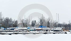 Sailboats moored in foggy harbor. Cold winter landscape with snow and ice