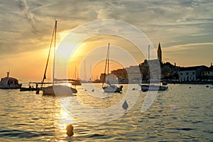 Sailboats at the Rovinj seaside and cityscape at Sunset.