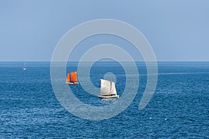 Sailboats sailing on deep blue ocean