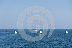 Sailboats sailing on deep blue ocean