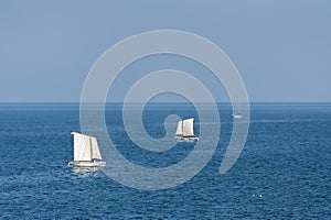 Sailboats sailing on deep blue ocean