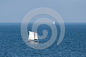 Sailboats sailing on deep blue ocean