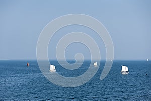 Sailboats sailing on deep blue ocean