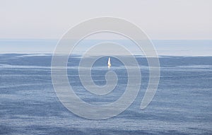 Sailing boat in a blue gradient from the sky to the ocean. It is a beautiful picture of a summer holiday