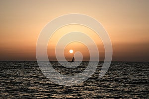 Sailing boat or boat off the shore of Libya with metallic reflecting water in the foreground at sunset