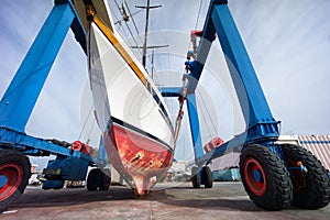 Sailing boat in boatyard on a crane photo