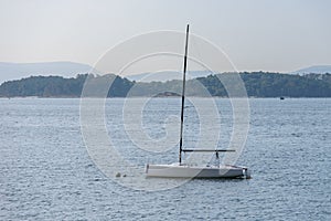 Sailing boat with deflated sails moored near the shore