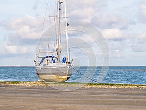 Sailing boat dried out at low tide of Waddensea on beach of nature reserve Boschplaat on Frisian island Terschelling, Netherlands photo