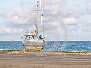 Sailing boat dried out at low tide of Waddensea on beach of nature reserve Boschplaat on Frisian island Terschelling, Netherlands