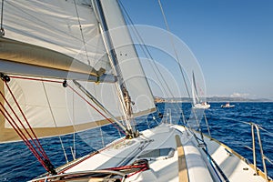 Sailing boat going fast on she's sails, view from the cockpit to bow.