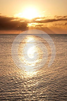 Sailing boat on horizon bathed in sun's rays