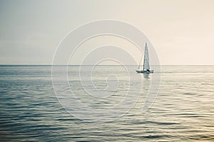 Sailing boat in open sea at sunset.