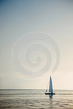 Sailing boat in open sea at sunset.