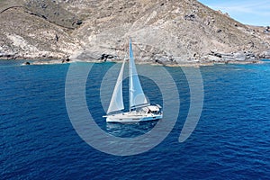 Sailing boat with open white sails, blue sky and rippled sea background