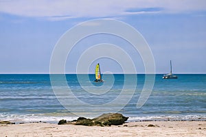 A sailing boat on peaceful ocean at summer, blue sea, sand beach