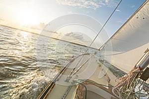 Sailing boat sailing fast into the beautiful sunset during choppy sea with tilted horizon