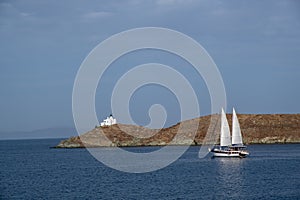 Sailing boat with white sails in the open sea, blue sky