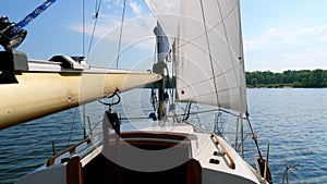 Sailing boat with white sails on the river.