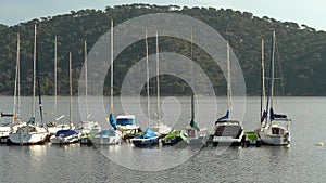 Sailing boats docked at the lake dock at sunset with green mountains in the background and sunset. San Juan, Madrid.