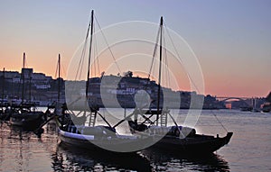 sailing boats loaded with barrels stand in a small port at sunset