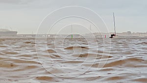 sailing boats return to port in heavy rain against the backdrop of the cityscape, view from the water level,