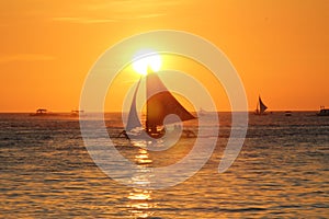 Sailing boats at sundowning with an orange sky and warm sunlight photo