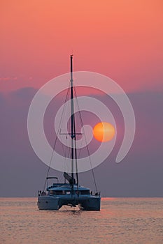 Sailing catamaran on a background of beautiful sunrise in the ocean