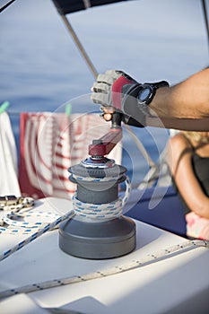 Sailing crew member pulling rope on sailboat