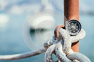 Sailing: nautical compass on a sailing rope, pier. Sailing boats in the background