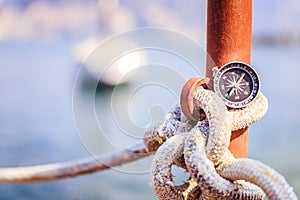 Sailing: nautical compass on a sailing rope, pier. Sailing boats in the background