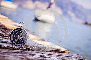 Sailing: nautical compass on wooden dock pier. Sailing boats in the background photo