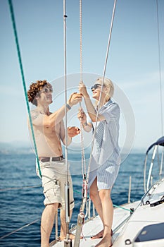 Young caucasian attractive couple navigating a yacht in caribbean sea