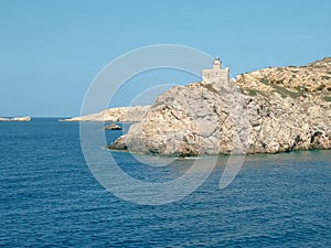 Sailing past the lighthouse in ormos harbor on the island of ios