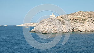 Sailing past the lighthouse in ormos harbor on the island of ios