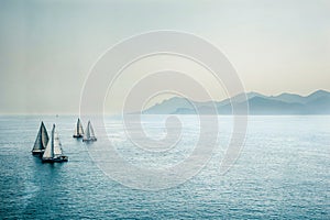 Sailing regatta or a group of small water racing boats in the Mediterranean, a panoramic view with blue mountains on a horizon