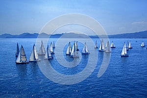 Sailing regatta, group of small water racing boats in Mediterranean, panoramic view with blue mountains on horizon on toning in cl