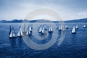 Sailing regatta, group of small water racing boats in Mediterranean, panoramic view with blue mountains on horizon on toning in