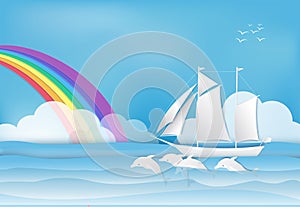 Sailing ship with Dolphin in the sea and rainbow on blue sky