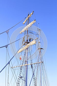 Sailing ship mast against a clear blue sky.