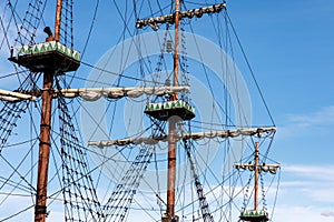 Sailing ship mast with rigging and cables against the sky.