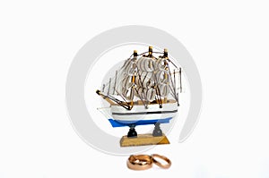 Sailing ship model with wedding rings isolated on white background
