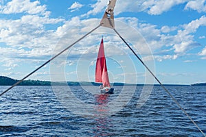 Sailing small yacht with red sails, visible from another boat through the rigging detail