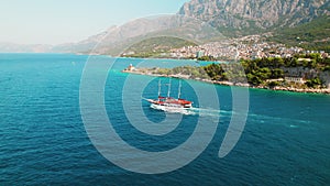 Sailing Vessel Cruises on Crystal Waters Near Makarska town in Croatia. The red and white ship floating against the