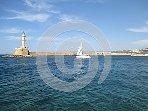 Sailing White Yacht near the Lighthouse at the Old Venetian Harbour of Chania, Crete Island, Greece