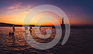 Sailing wind boats at sunset near lighthouse and sea port Varna, Bulgaria. Sport competition