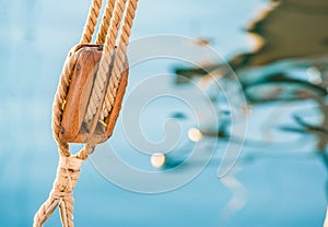 Sailing, wooden pulley with nautical ropes and blue sea water